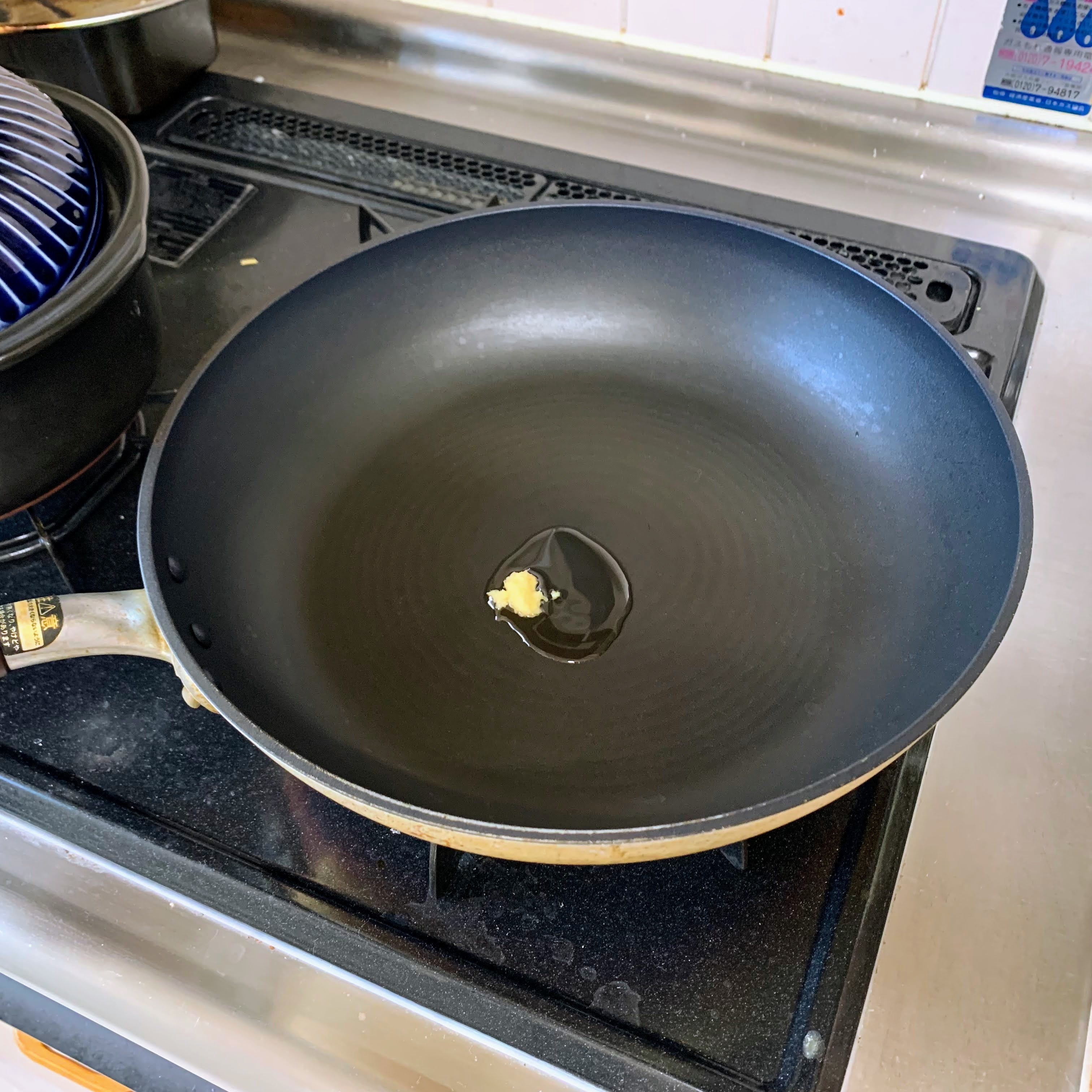 Adding the grated ginger to a large fry pan