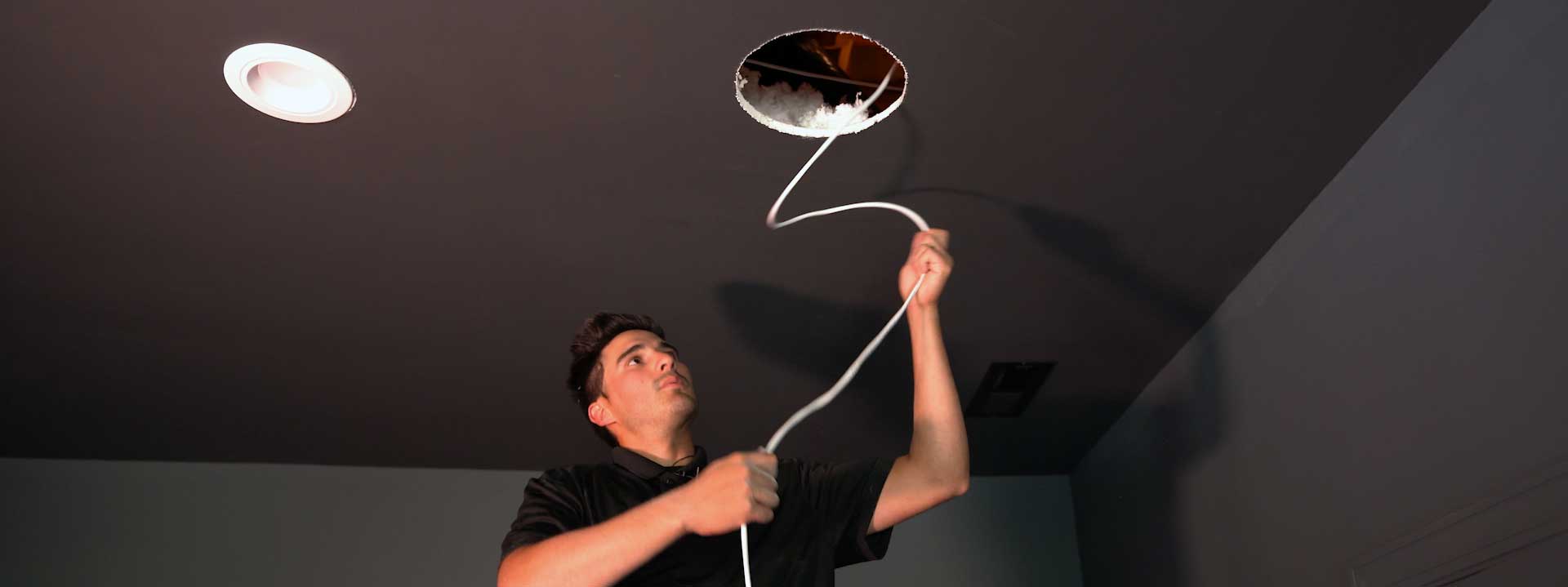 Installer running wire for in-ceiling speaker