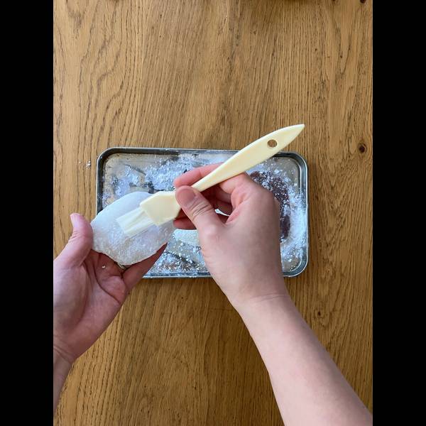 Dusting excess starch off of the mochi with a brush