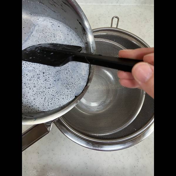 Straining the black sesame pudding into the large bowl over an ice water bath