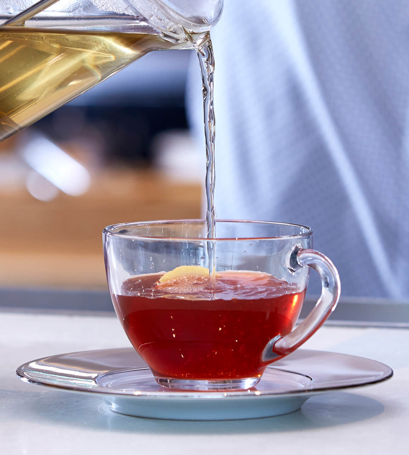 Pouring a cup of bombay chai tea into a glass cup