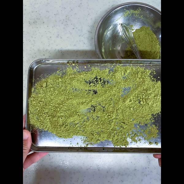 Sprinkling the kinako matcha powder mixture onto a tray