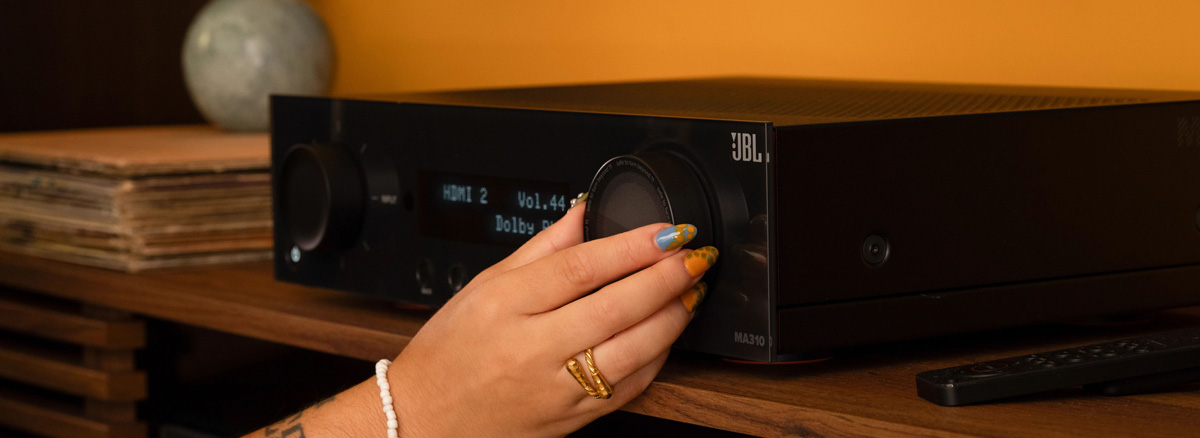 JBL MA310 AV Receiver with a hand on the dial