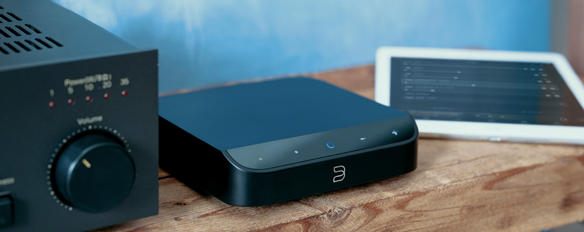 Bluesound NODE on a shelf beside a tablet