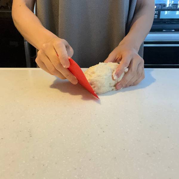 Using a bench scraper to wipe away any sticky pieces of dough