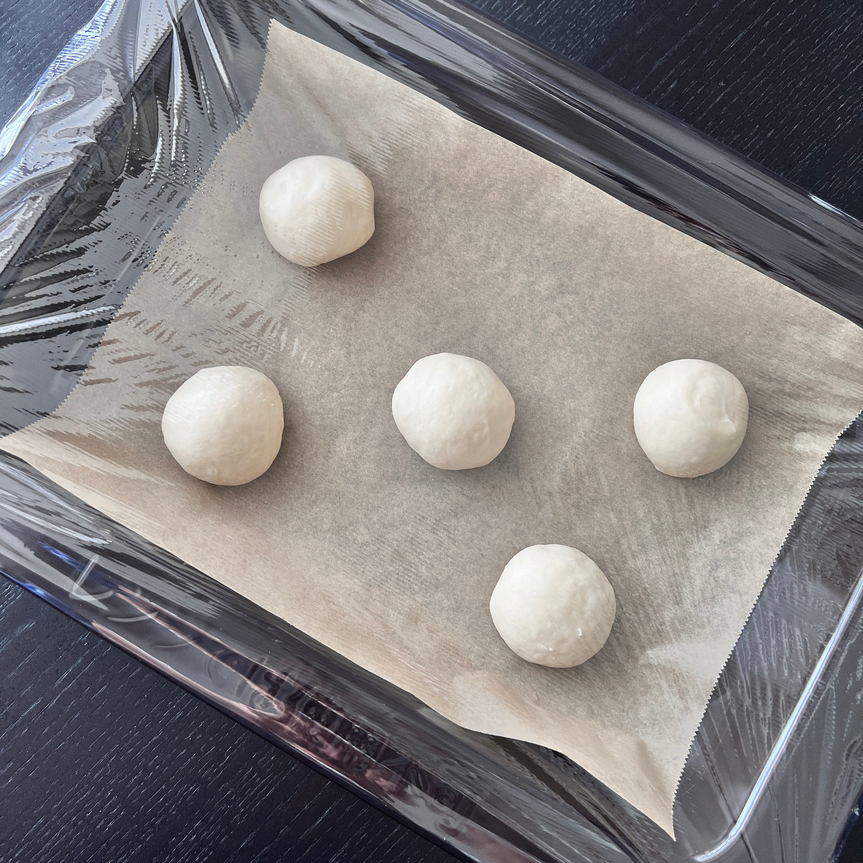 Covering dough in plastic wrap
