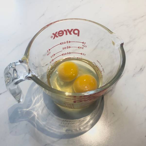 2 eggs cracked inside of a measuring cup