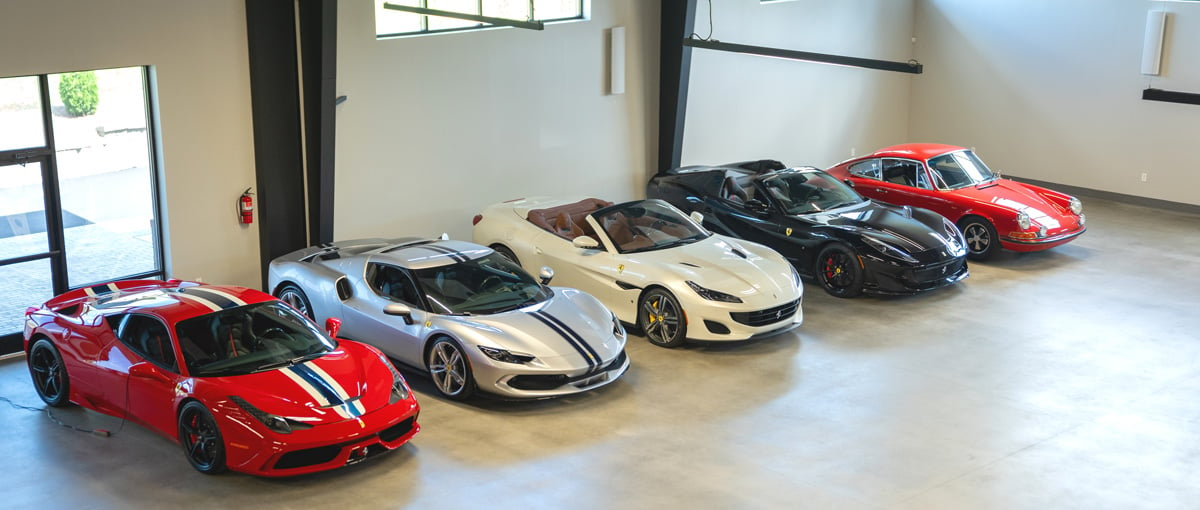 5 cars on display and lined up against the wall of a car garage