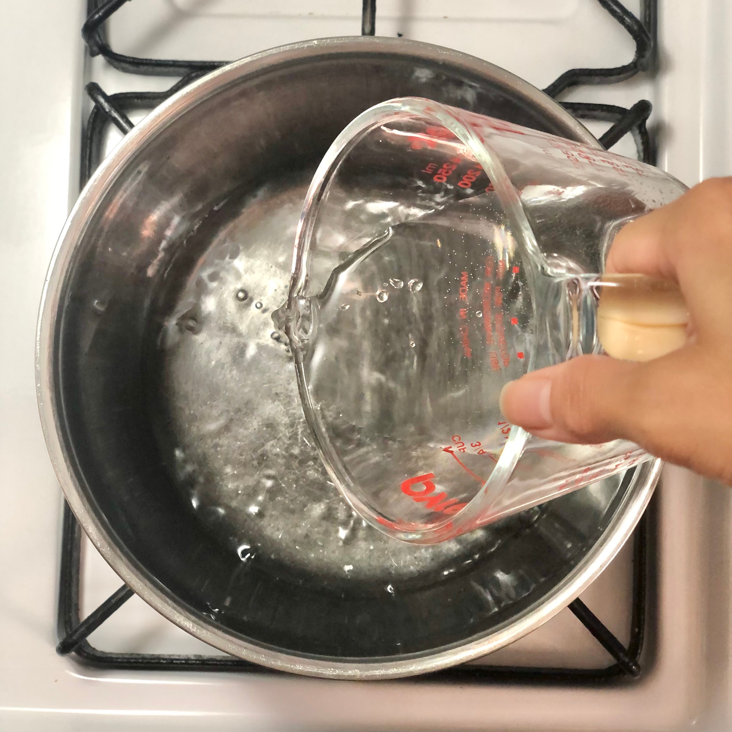 Adding water to a saucepan