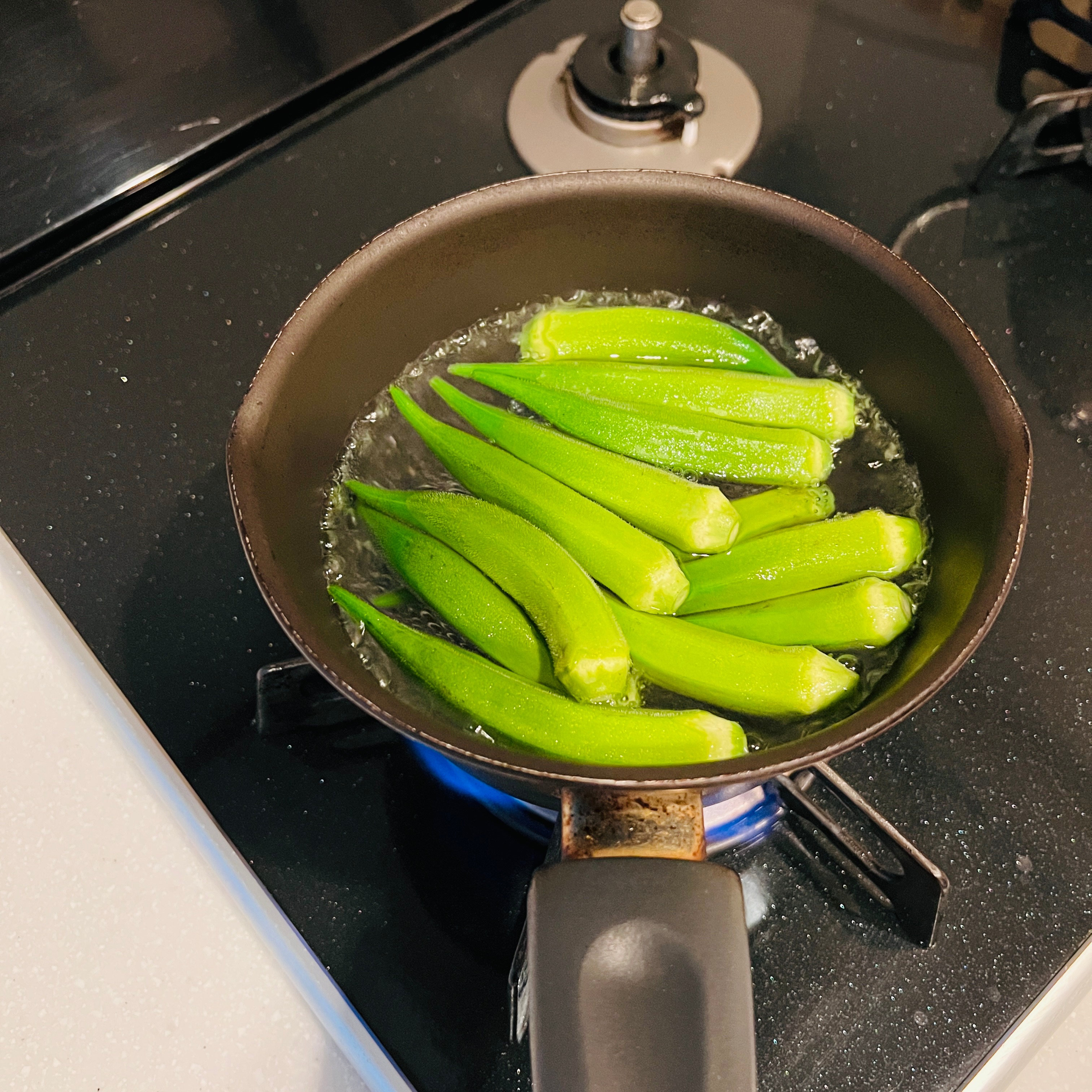 Blanching the okra in a small pot