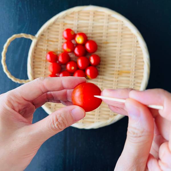 Pricking the cherry tomatoes with a toothpick