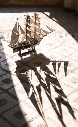Miniaturholzschiff mit Schatten auf dem Boden