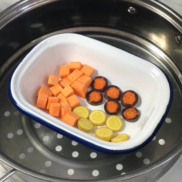 Placing the sweet potatoes and carrots into a steamer