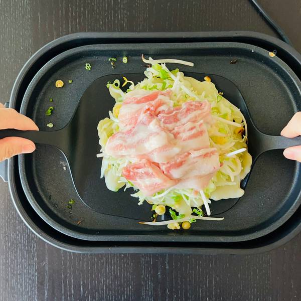 using two turners to flip the okonomiyaki