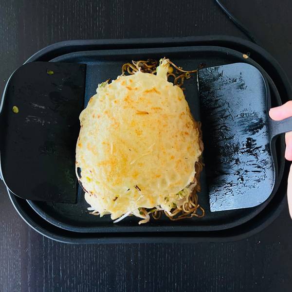 Piling the okonomiyaki on top of the egg