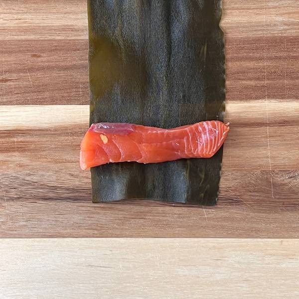 adding a piece of salmon inside of the kombu