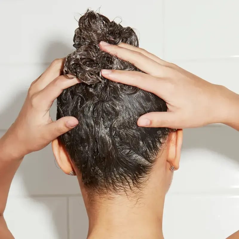 Closeup of Odele Scalp and Body Scrub being massaged into wet hair 
