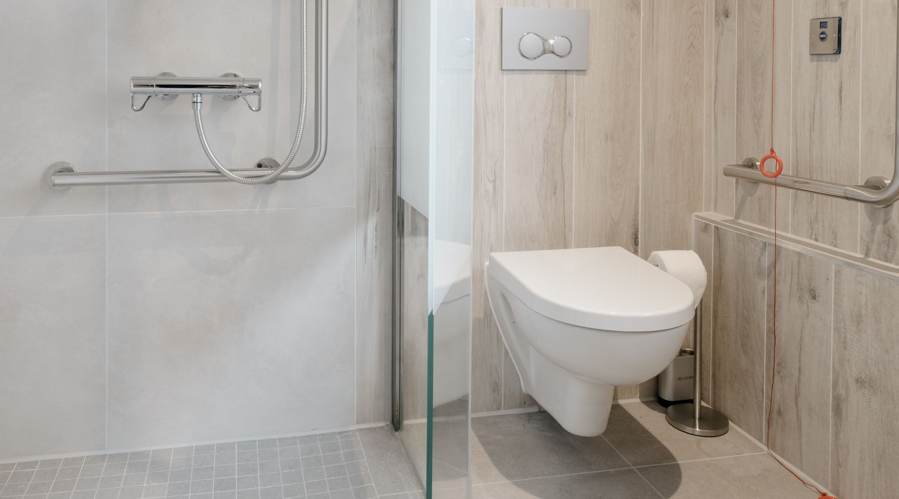 Trinity Lodge future-proofed, accessible apartment wetroom/bathroom featuring toilet, supportive L-shaped shower riser, grab rails and emergency pull cord 