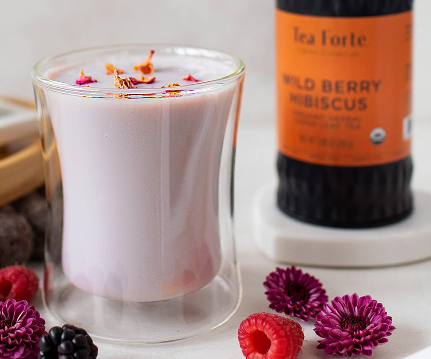 Wild Berry Hibiscus Latte in a POOM glass with a loose tea canister