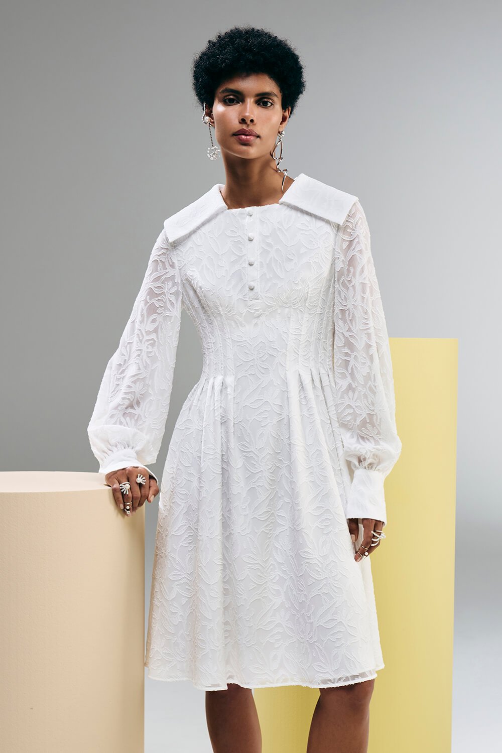 Model wears a white lace detailed dress