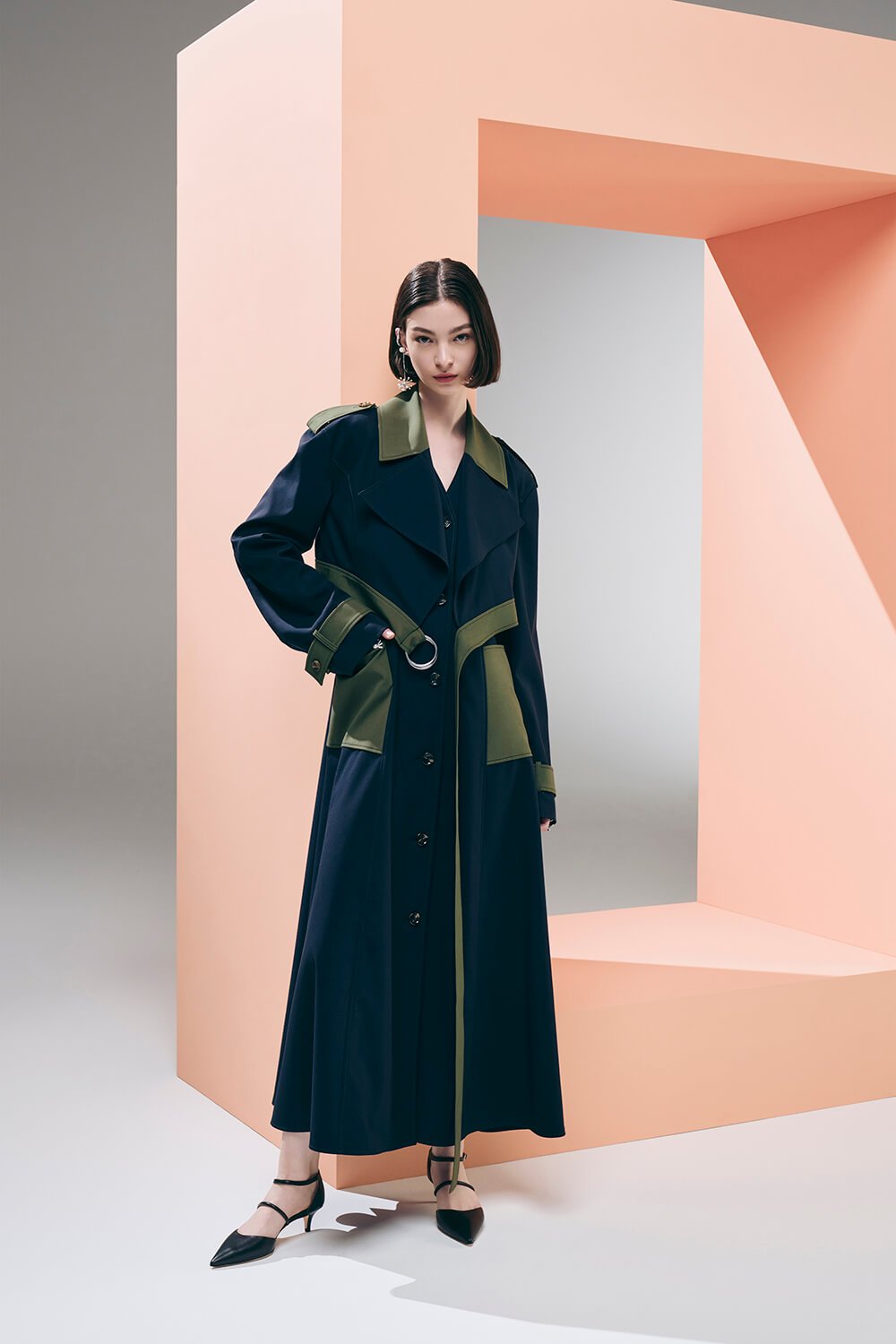 Model wears a navy and green trench coat