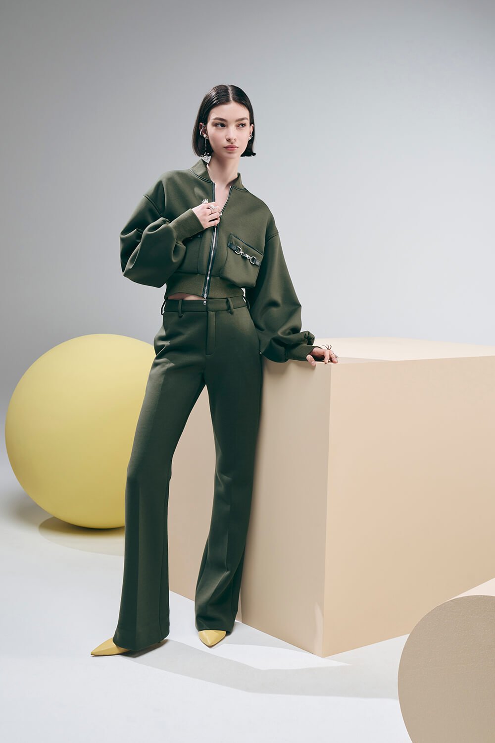 Model wears a green set with trousers and bomber jacket