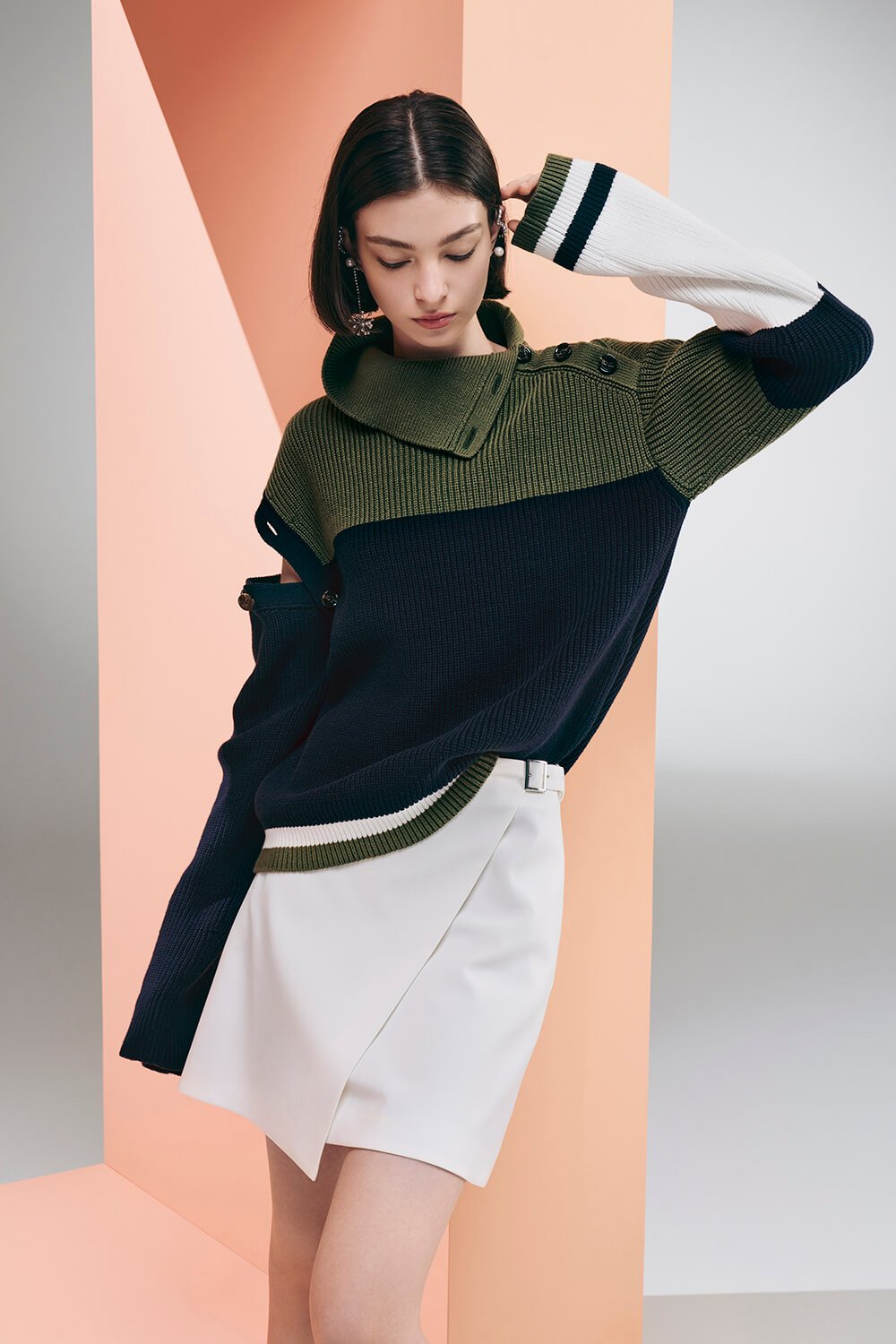 Model wears a white skirt with a tri color sweater (navy, green, white)
