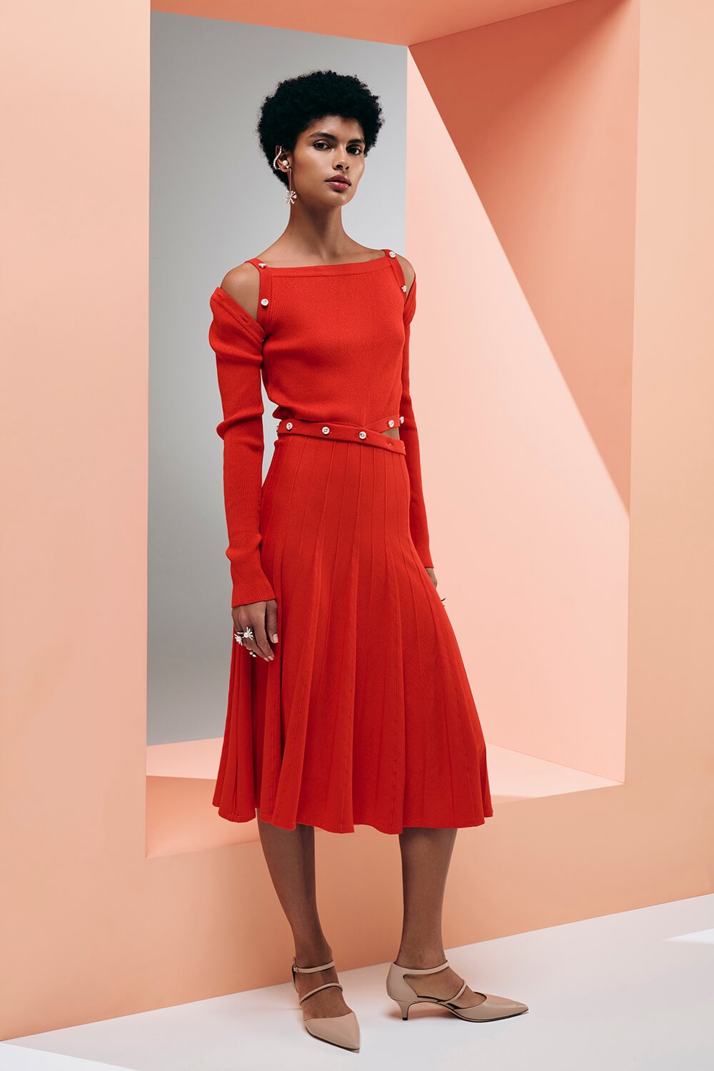 Model wears an orangey/red knit midi dress with button details