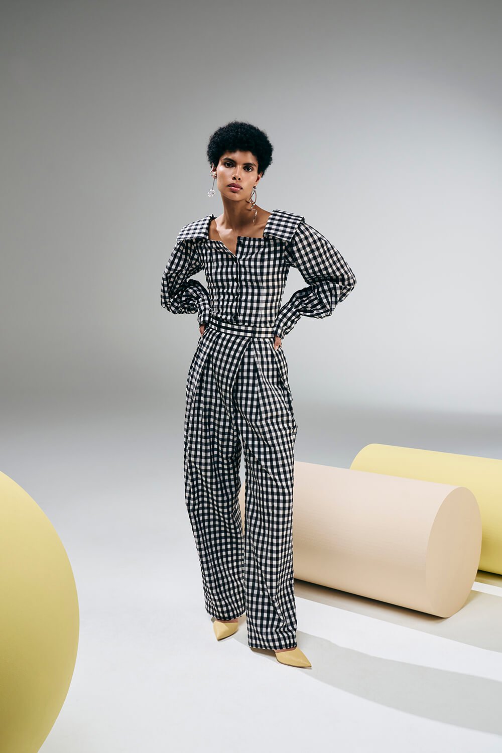 Model wears a white and black checkered trousers with long sleeve collared top