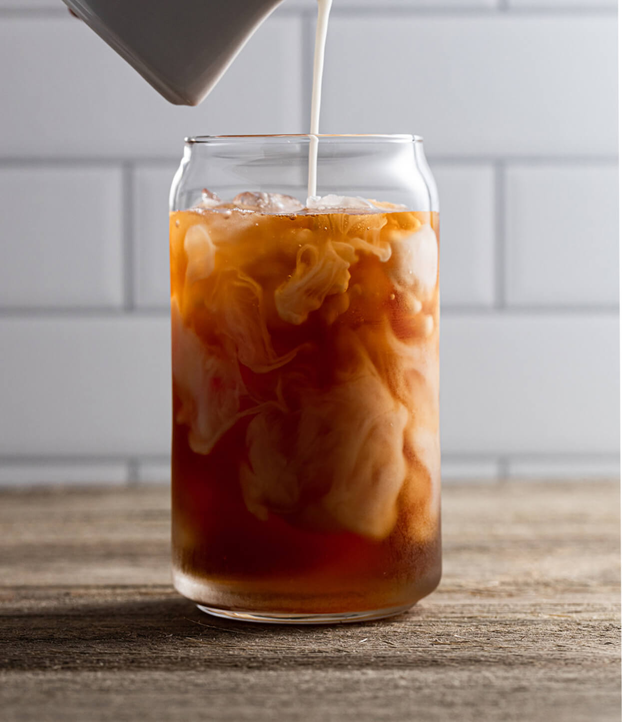 Pouring milk into a glass of Orchid Vanilla iced tea