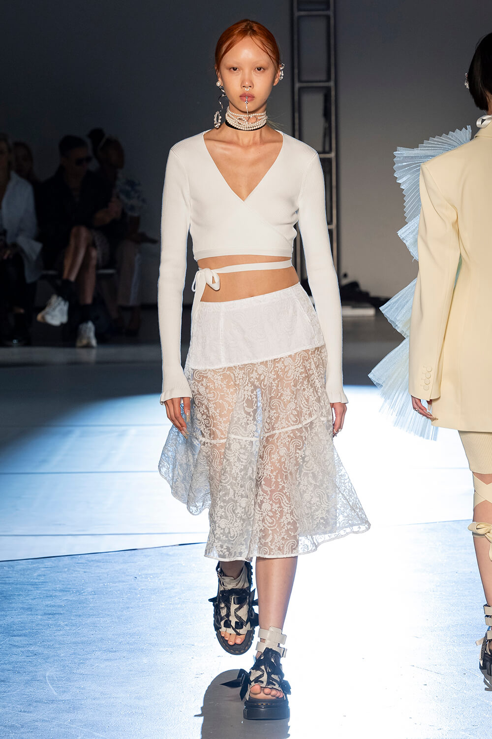 Model wears a white wrap cardigan with a lace white skirt