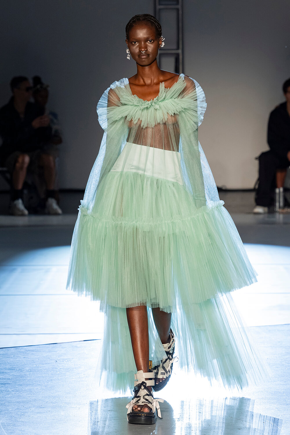 Model wears a long green tutu with a ruffle top 