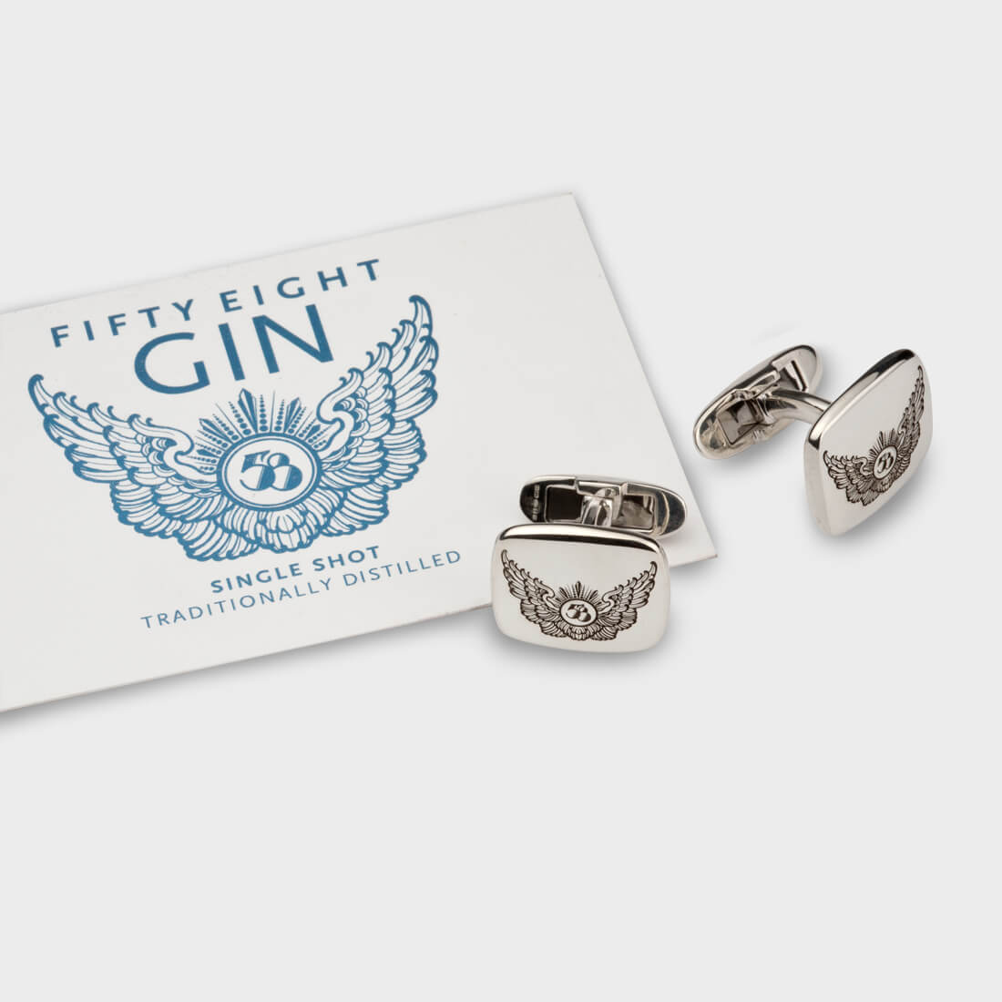 Sterling silver signet cufflinks with Fifty Eight Gin's wings logo engraved on it, next to a business card of Fifty Eight Gin brand