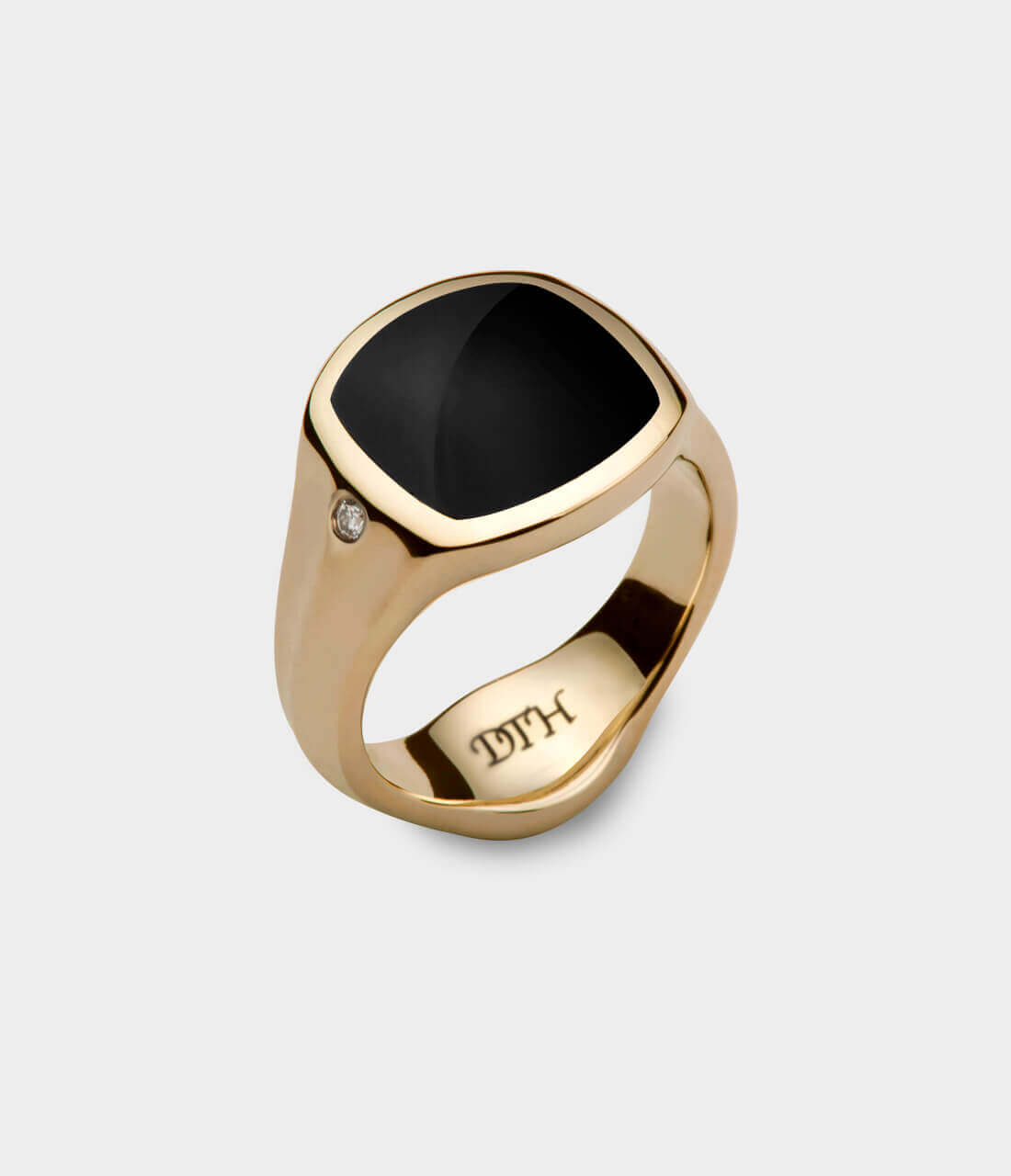 A yellow gold signet ring inlaid with black onyx and the letter DTH engraved on the inside bottom of the ring. A diamond stone is set on the side of the signet