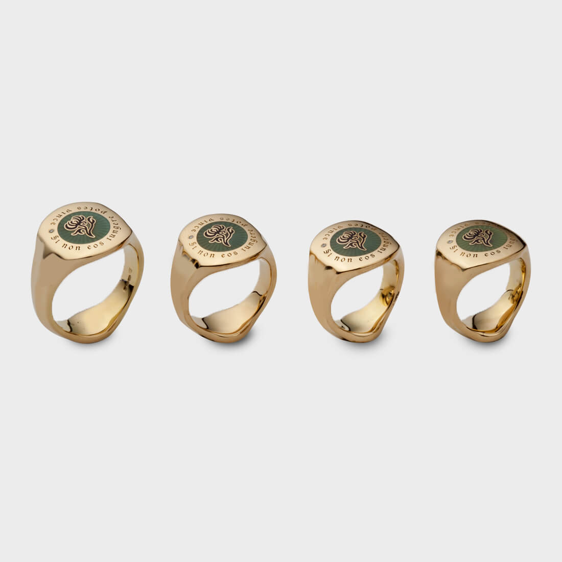 Four yellow gold signet rings in different sizes with the same family crest engraved on their top surface in green colour and black letters