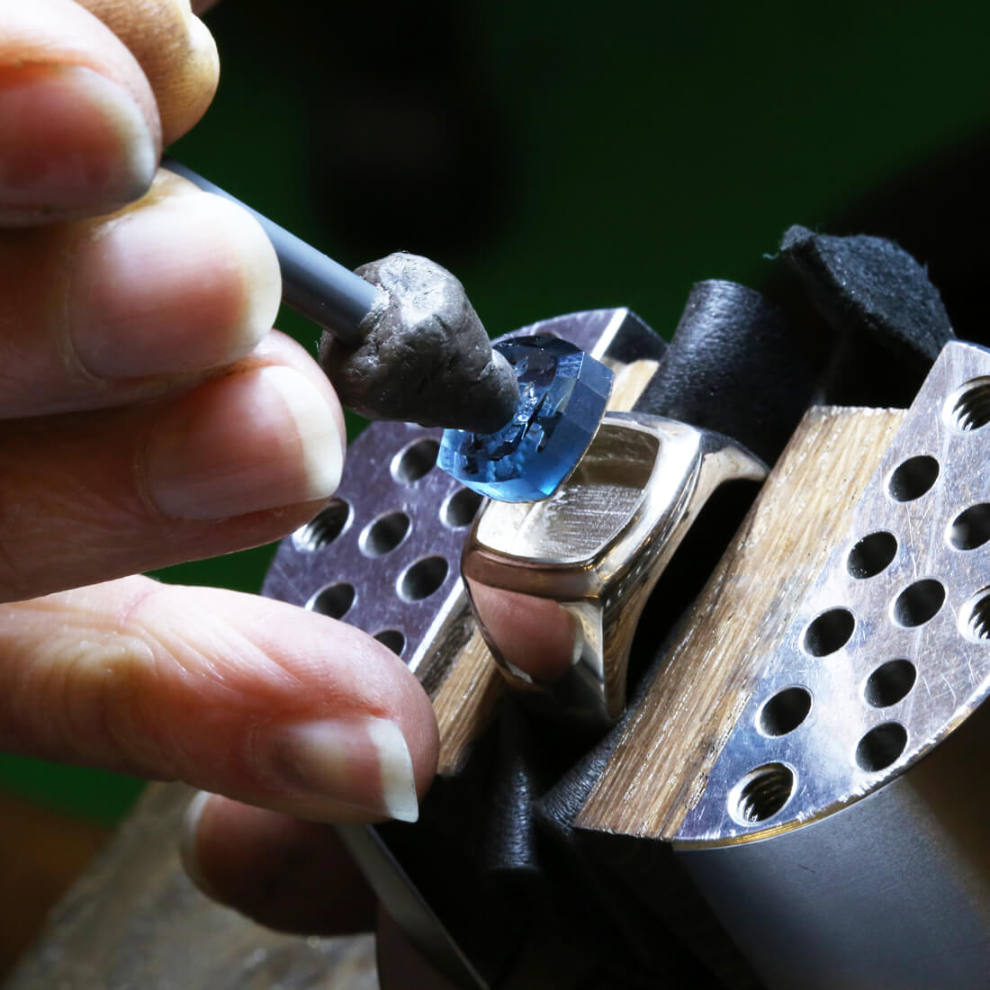 A jeweller's hand is setting a intaglio blue stone in a silver signet ring in our workshop