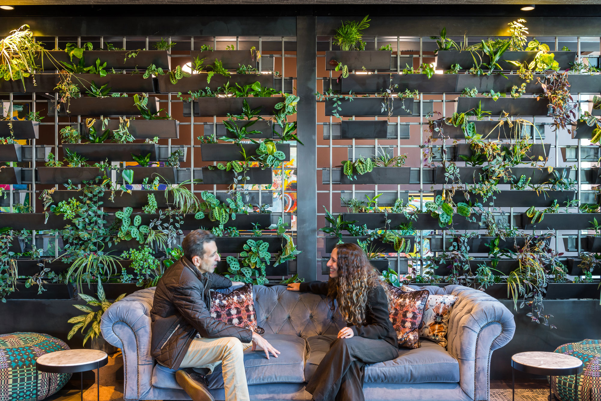 two people seated on a sofa talking in front of a biophilia living wall in Barclays' office