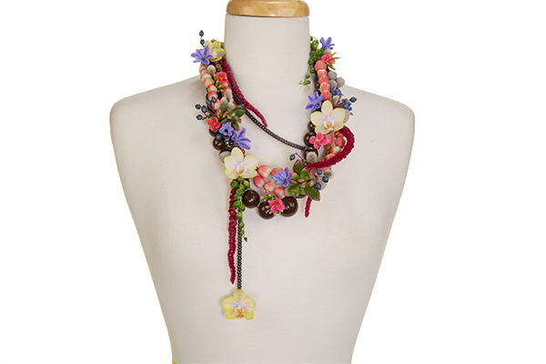A finished floral necklace is displayed on a mannequin.