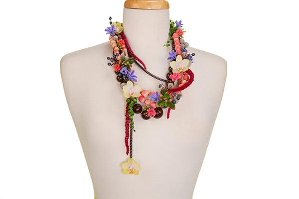 A finished floral necklace is displayed on a mannequin.