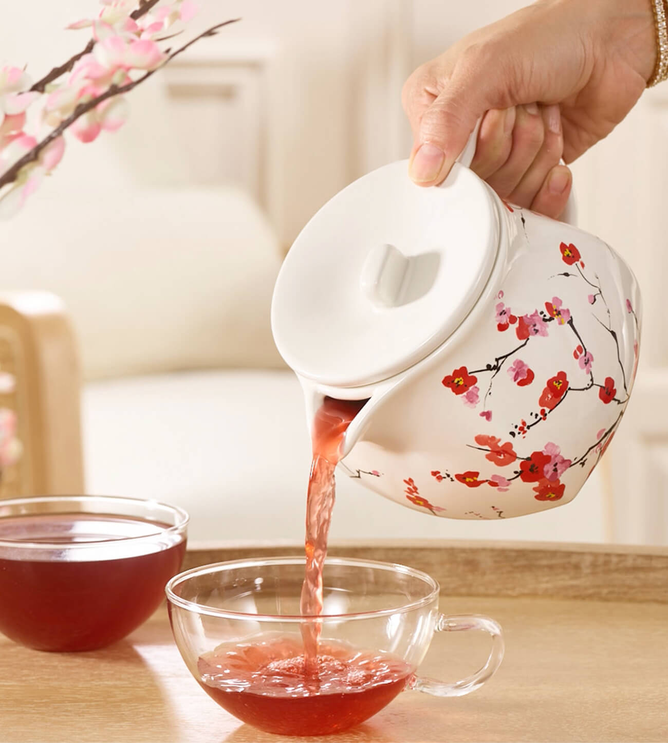 Sakura Teapot pouring tea into a glass cup