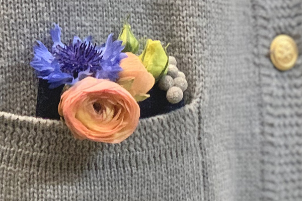 A casual contemporary corsage filled with beautiful blooms including ranunculus can be tucked into the pocket of a sweater or jacket for a stylish look.