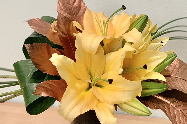 This lovely floral design mixes lilies, aspidistra, lily grass, and color enhanced crocodyllus and fatsia leaves for creative balance and beauty.