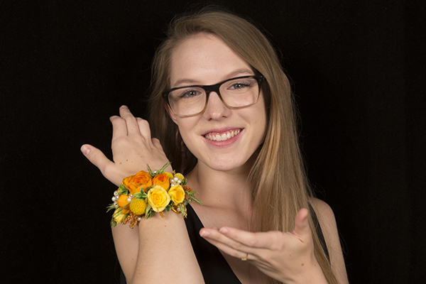 A gorgeous, over-the-top homecoming cuff with lots of bling is covered in orange roses, bright yellow spray roses, and sunshine colored craspedia for a beautiful style.
