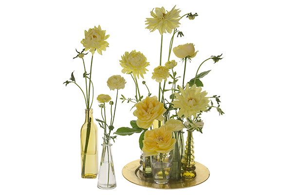 Lovely summer blooms in sunny yellow palette are placed in a variety of unique and colorful glass bottles, large and small, for a beautiful effect.