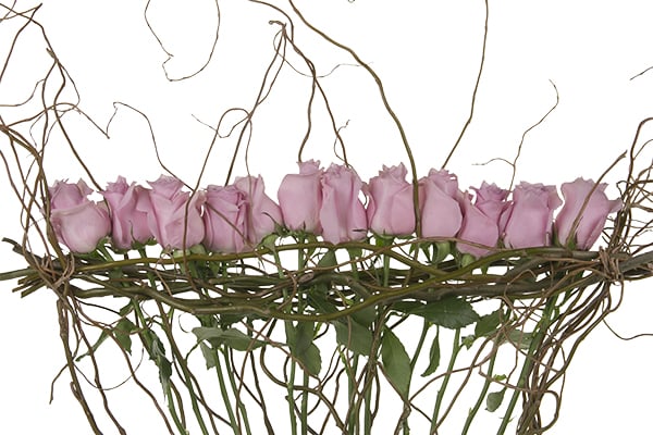 Pink roses are showcased in a dramatic contemporary Mother's Day floral design which uses curly willow as a natural armature and Israeli ruscus to cover the foam base mechanics.