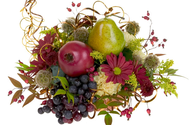 A contemporary cornucopia is a festive harvest centerpiece filled with grapes, pears, pomegranates, mums, scabiosa pods, carnations, solidago, fall leaves, rose hips, and a bit of flat wire for sparkle.
