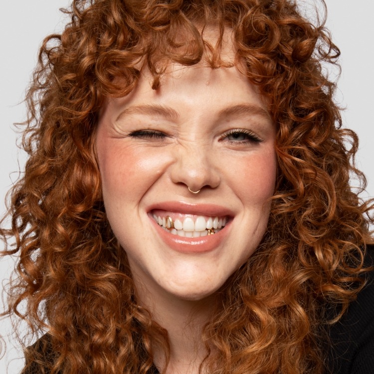 Model wears a full face of Milk Makeup products, including Lip + Cheek, KUSH Mascara, and more, against a white background.