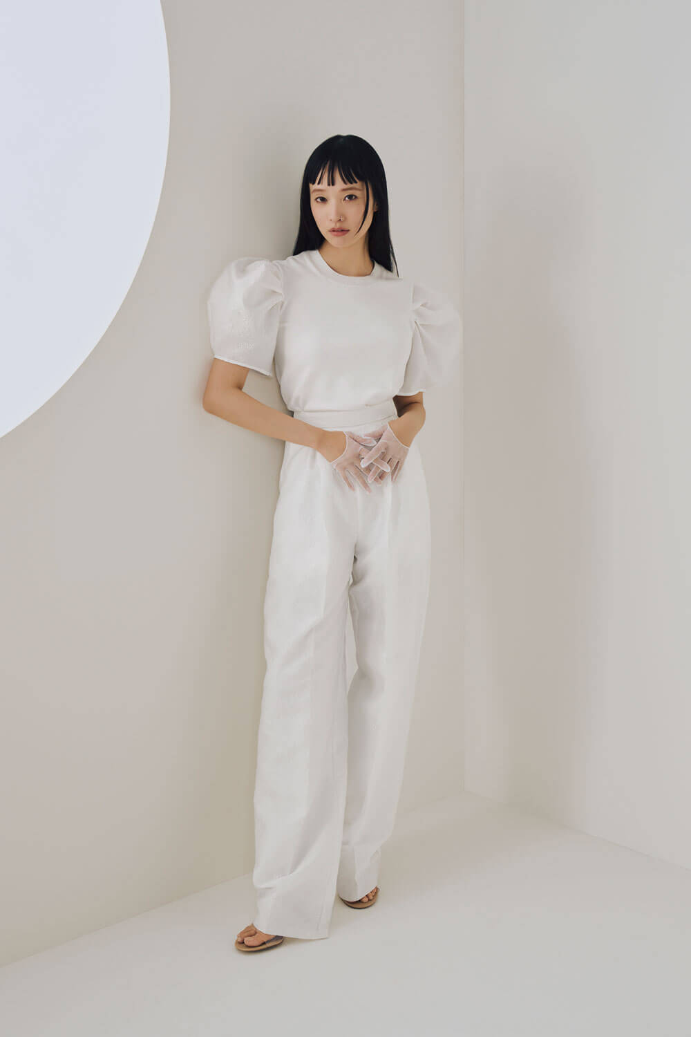 Model is wearing white trousers and a white top 