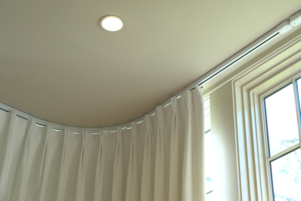 Drapes and drapery track on the ceiling of a bedroom