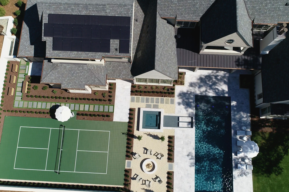 Aerial view of backyard with pickleball court, swimming pool, and fire pit.